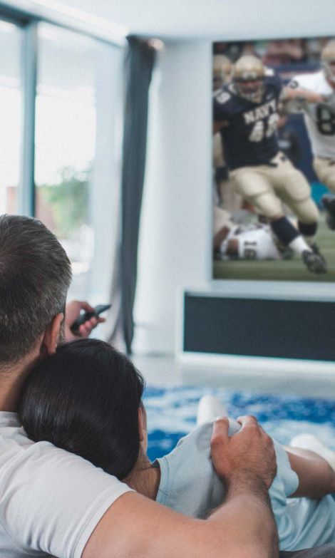 man and woman watching tv on a couch